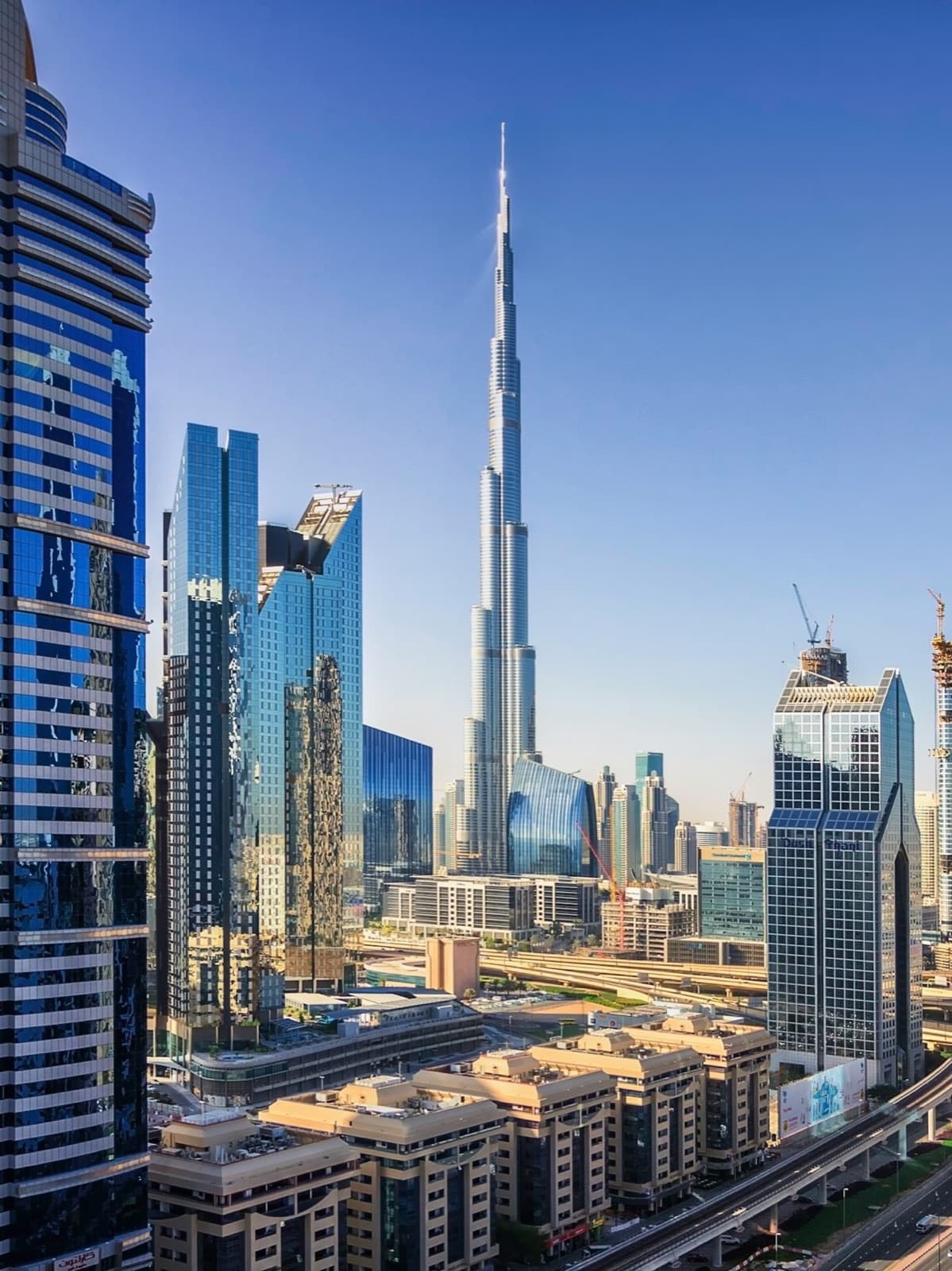 Downtown Dubai's residential and office towers with the Burj Khalifa against a clear blue sky
